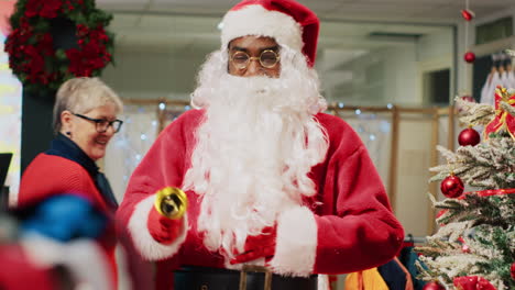 Worker-dressed-as-Santa-Claus-entertaining-shoppers-in-xmas-adorn-fashion-store-during-winter-holiday-season.-Retail-assistant-sharing-festive-spirit-with-customers-visiting-clothing-shop