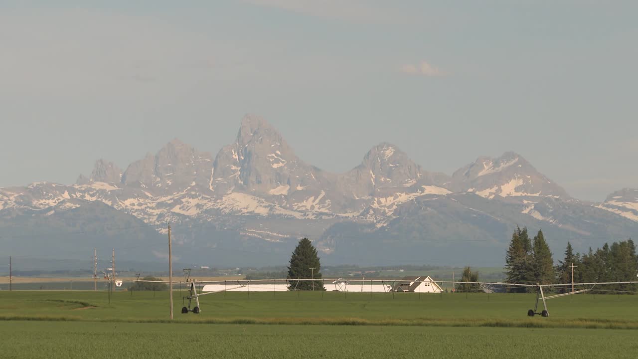 Campi agricoli dell'Idaho sotto le imponenti montagne Teton in una calda giornata estiva