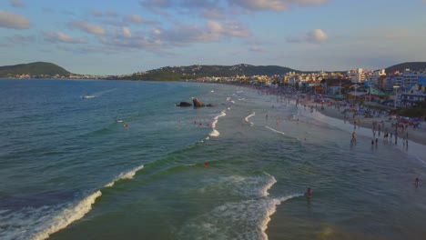 toma aérea volando sobre las olas del mar junto a la playa bombas en brasil a la hora dorada