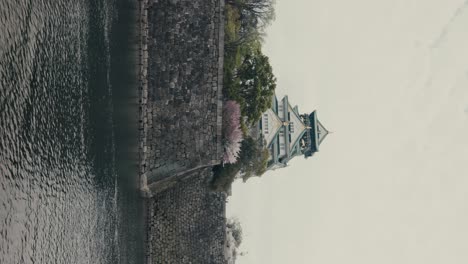 Vertical---Tilt-down-Revealing-Shot-Of-Famous-Osaka-Temple-And-Its-Moat-In-Osaka,-Japan