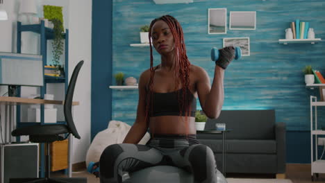 mujer atlética en forma con piel oscura haciendo ejercicios musculares con pesas de fitness