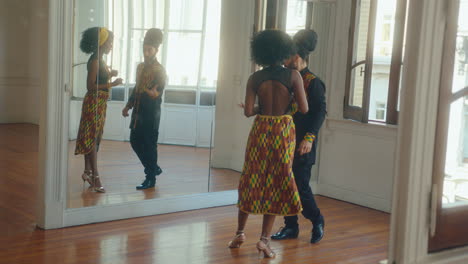 black woman learning tango with male instructor in dance studio
