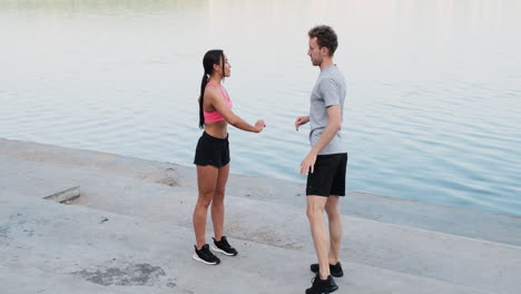 sportive couple warming up and stretching near the river