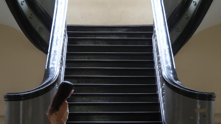 Escadaria dentro do histórico Palácio Gia Long em Ho Chi Minh, Vietnã, com mulher subindo.