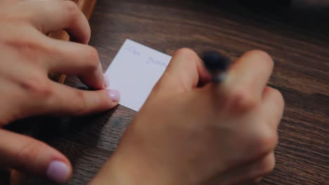 the girl writes a note on a small piece of paper lying on the floor. close-up from above