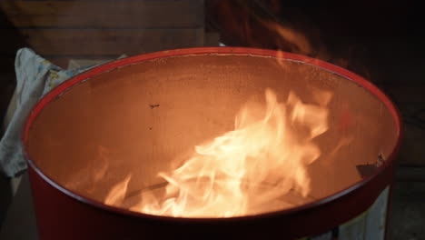 fuego o llama dentro de un barril de metal por la noche en las calles de la ciudad