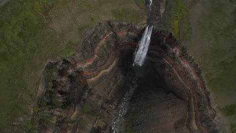 Toma-Aérea-De-Arriba-Hacia-Abajo-De-Un-Barranco-Profundo-Y-Empinado-Con-Una-Cascada-Que-Cae-En-Islandia-Durante-El-Día---Cascada-Hengifoss-épica-En-El-Valle-Del-Cráter-Gigante