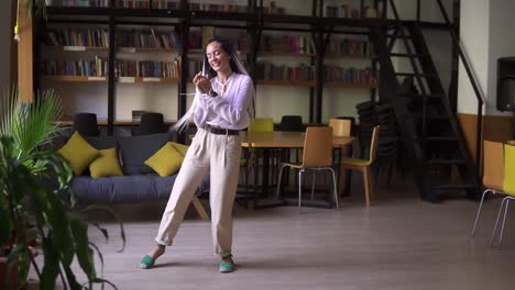 portrait of joyful dreadlocks female happy student funky dancing in library after getting the best grade on exam. bookcase in background. full length. slow motion