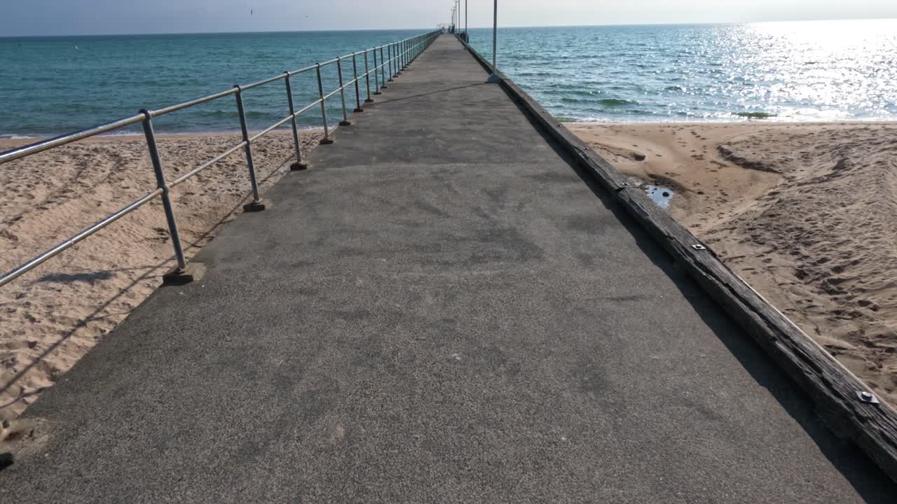 Walking along a pier towards the sea