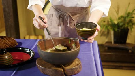 mujer con ropa tradicional japonesa sirviendo sopa de miso