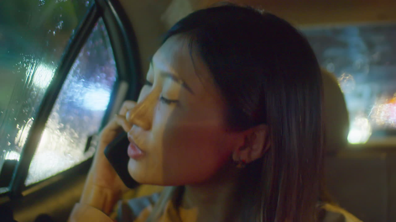 Asian Woman Talking on Phone during Car Ride at Night