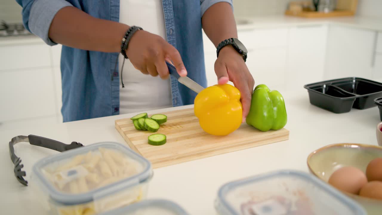 Vertikales Video: Beginnt mit dem Gurkenschneiden, Mann in Jeans bereitet zu Hause Mahlzeiten vor, schneidet Paprika.