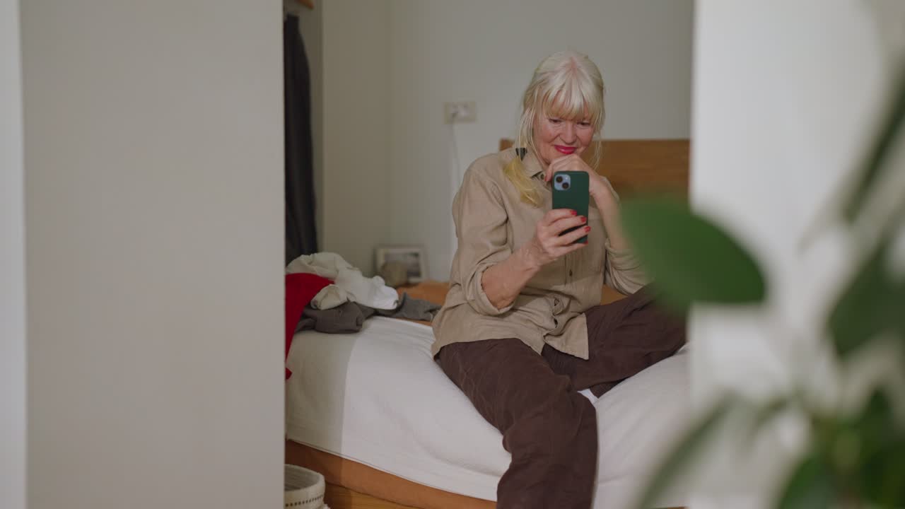 Senior woman using a phone in her bedroom