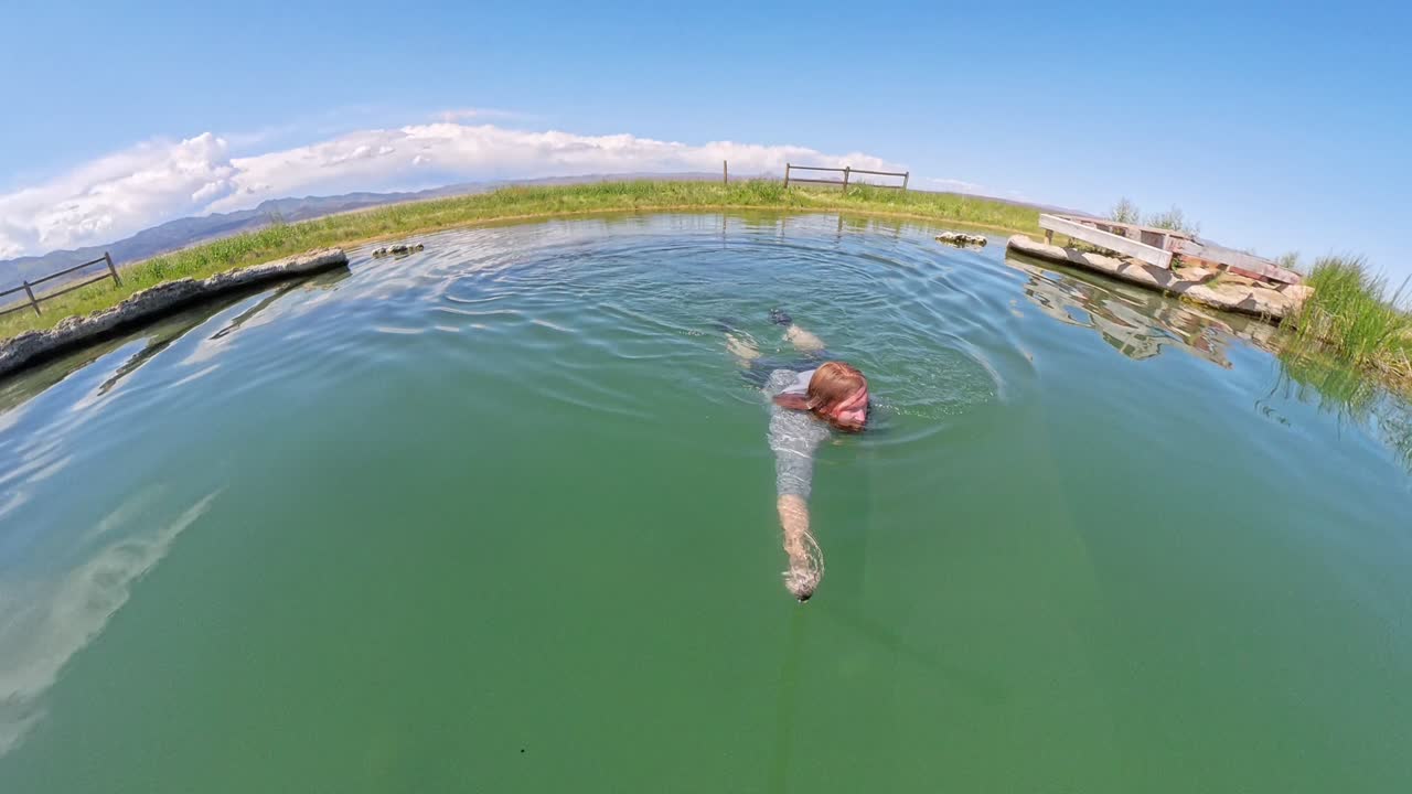 Hot Spring in Utah with a red haired male jumping in and swimming