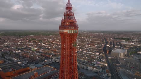 blackpool tower red painted steel glowing at golden hour with urban sprawl behind. lancashire, uk.