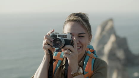 close up of a blonde woman taking photo in mountains during hiking adventure