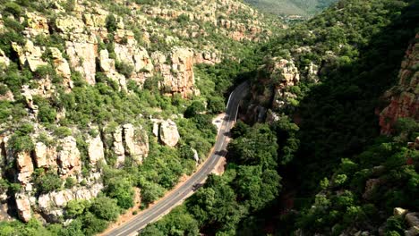 Car-passing-mountain-pass-with-green-trees,-panning