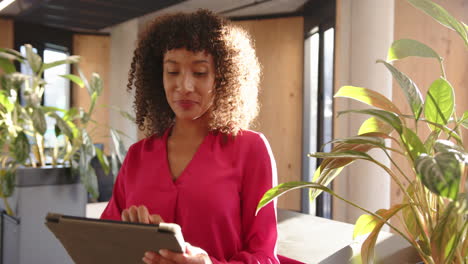 using tablet, woman in pink blouse working in modern office environment