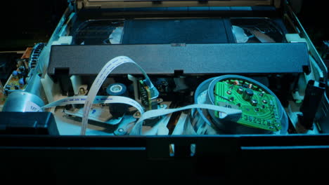 old video recorder inside close-up, vhs. retro player in neon blue light, vintage video cassette broadcasting, audio tape.