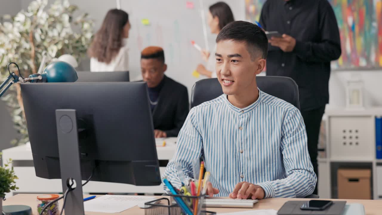 A man of Asian-Korean beauty is sitting an office computer, using a web ...