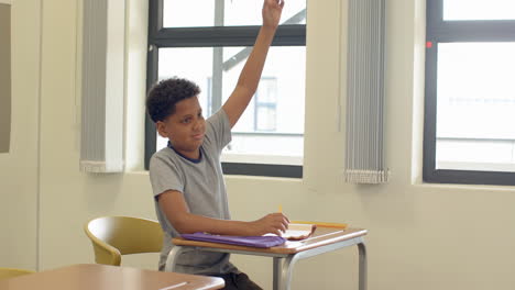 in classroom, boy sitting at desk with notebook, looking thoughtful, at school