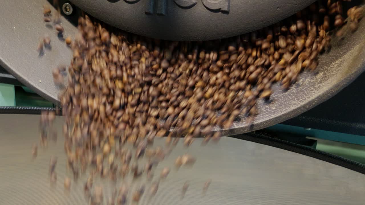 Witness the transformation of raw coffee beans into aromatic grounds in an industrial coffee roasting process.