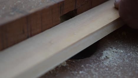 An-extreme-close-up-of-a-router-table-bit-milling-wood,-which-is-being-pushed-through-by-a-hand