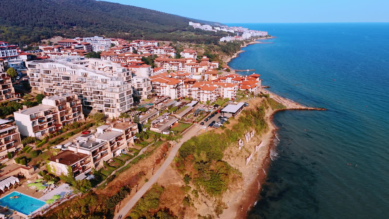 Seaside resort with yachts and red roof houses on the coast. Aerial view of a seaside resort with yachts, red roof houses and mountains along the coast