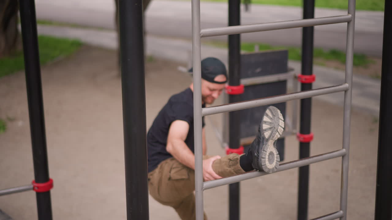 White Man Exercises On Park Bars Skillfully, Controlled Muscle Movements While Balancing On Urban Park Equipment, Man Performs Controlled Balancing And Stretching Exercises On Outdoor Bars In City