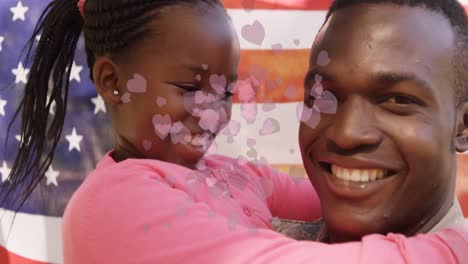 animation of hearts and american flag over happy african american father with daughter