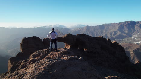 hiker admires the window of roque bentayga at sunset in gran canaria.