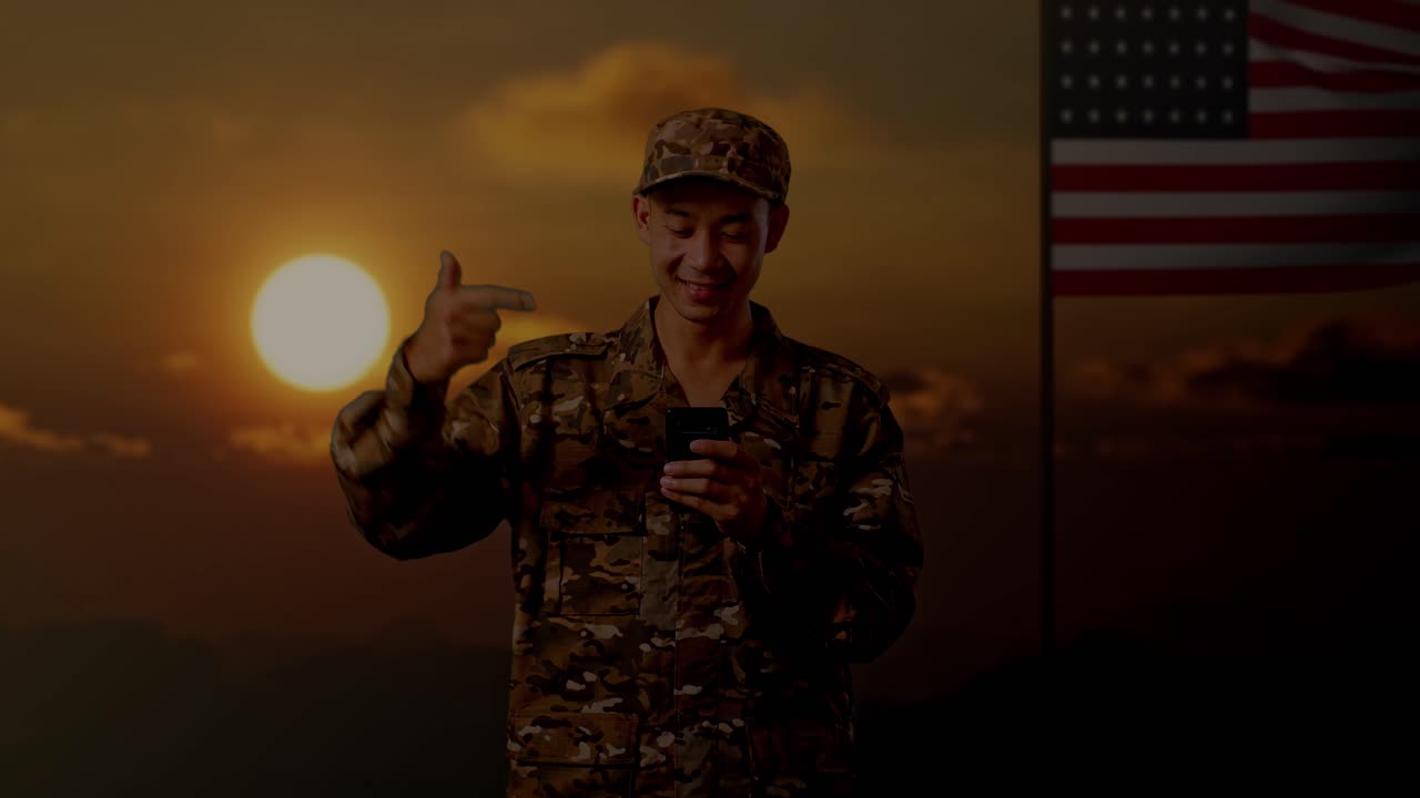 hombre militar usando un teléfono inteligente al atardecer con el fondo de la bandera estadounidense