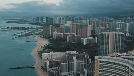 panning aerial drone slowly flying over a colorful honolulu skyline while sunset in oahu, hawaii with waikiki beach as a special point of interest.