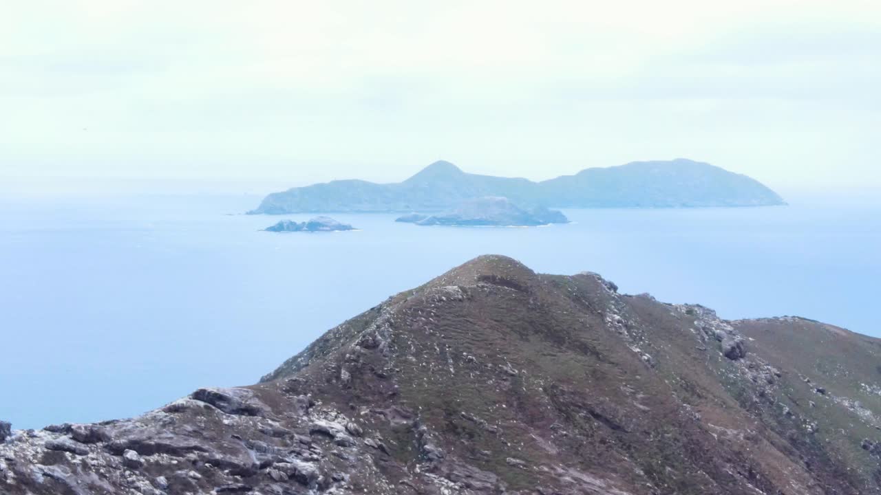 Aerial reveal ascend of the rocky coastline of Coronado Islands, Mexico, showcasing rugged terrain and surrounding blue waters