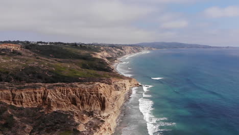 las olas chocan cuando el dron gira alrededor de los acantilados en torrey pines