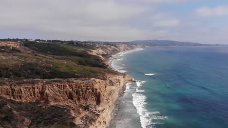 waves crash as drone rotates around cliffs at torrey pines