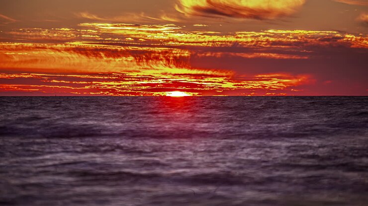 View of the sunset in timelaps over the horizon on the background of the ocean