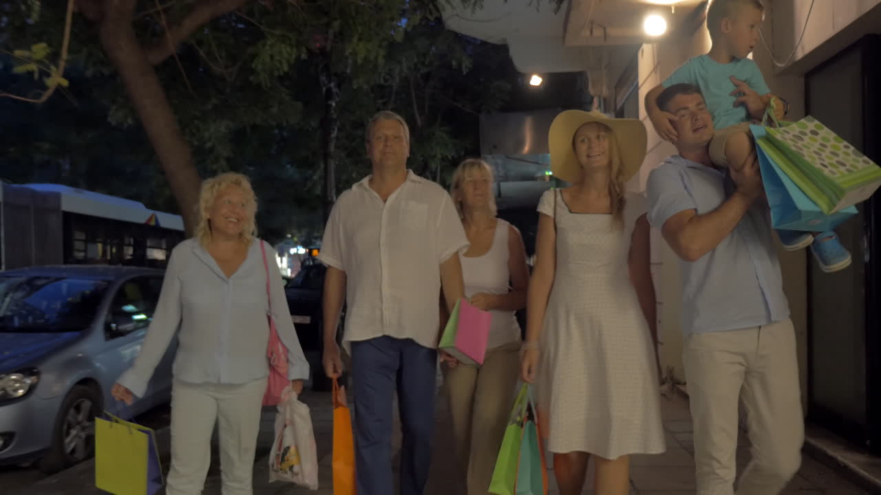 가게 들 이 있는 거리 에서 쇼핑 가방 을 들고 있는 가족