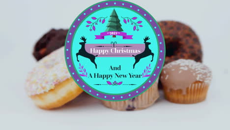 animation of christmas greetings on tag over cupcakes on white background