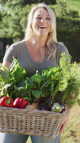 video vertical de una mujer caucásica sonriente sosteniendo una canasta con verduras frescas