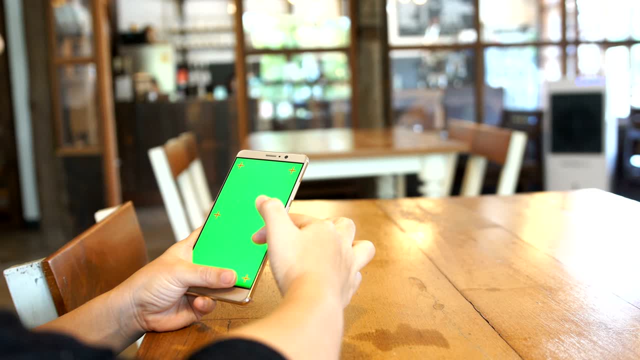 카페에서 녹색 화면에서 스마트 폰을 사용하는 여성.