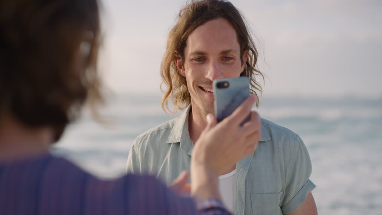 joven feliz posando para una foto en una playa soleada amigo tomando fotos usando la cámara del teléfono inteligente vacaciones recuerdos de viajes personas reales serie