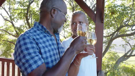 happy senior african american couple drinking wine on sunny terrace, slow motion