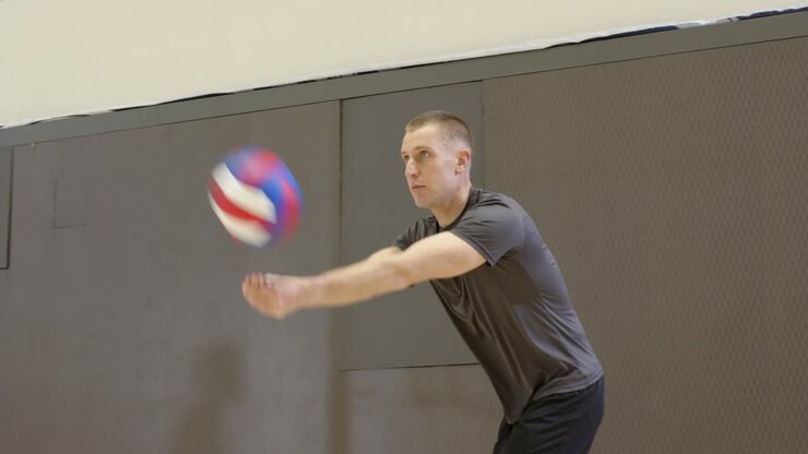 Diverse male players spiking volleyball after pass, gray tee attacker jumping at net in gym scoring