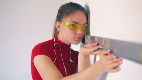 woman with earphones checks wall level in spacious room