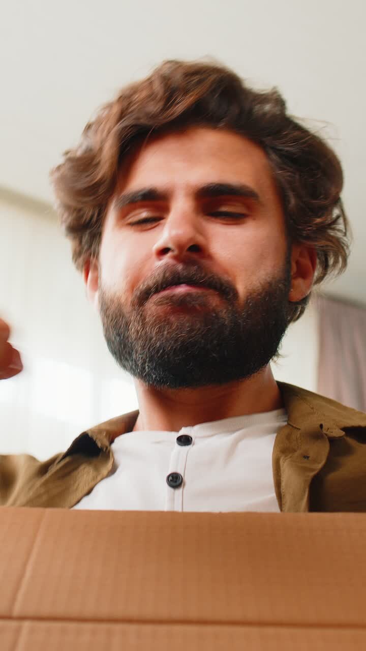 Un uomo arabo felice che compra, che spacca una scatola di cartone, che consegna un pacco, che compra online, che compra a casa.