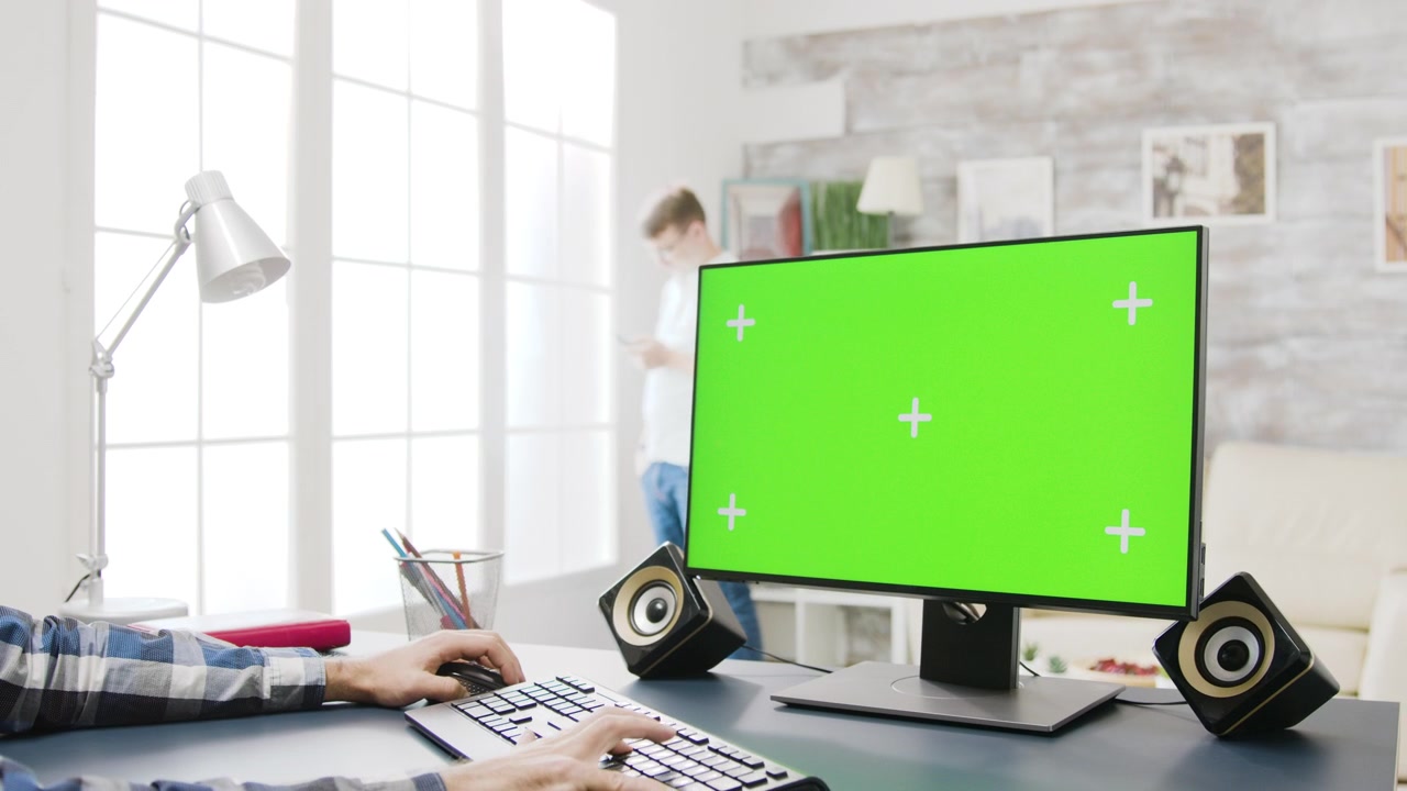 Man Working on Computer with Green Screen Monitor in Home Office