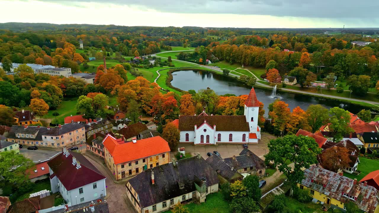 Veduta aerea di un pittoresco villaggio con chiesa e lago in autunno.
