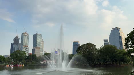 lumpini park bangkok thailand green space water pond sprinkle, city buildings skyline