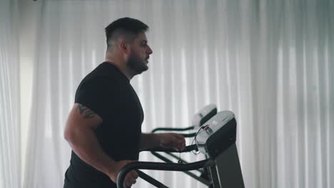 sterke man die cardio-oefening traint op loopbandmachine in zijaanzicht van de sportschool